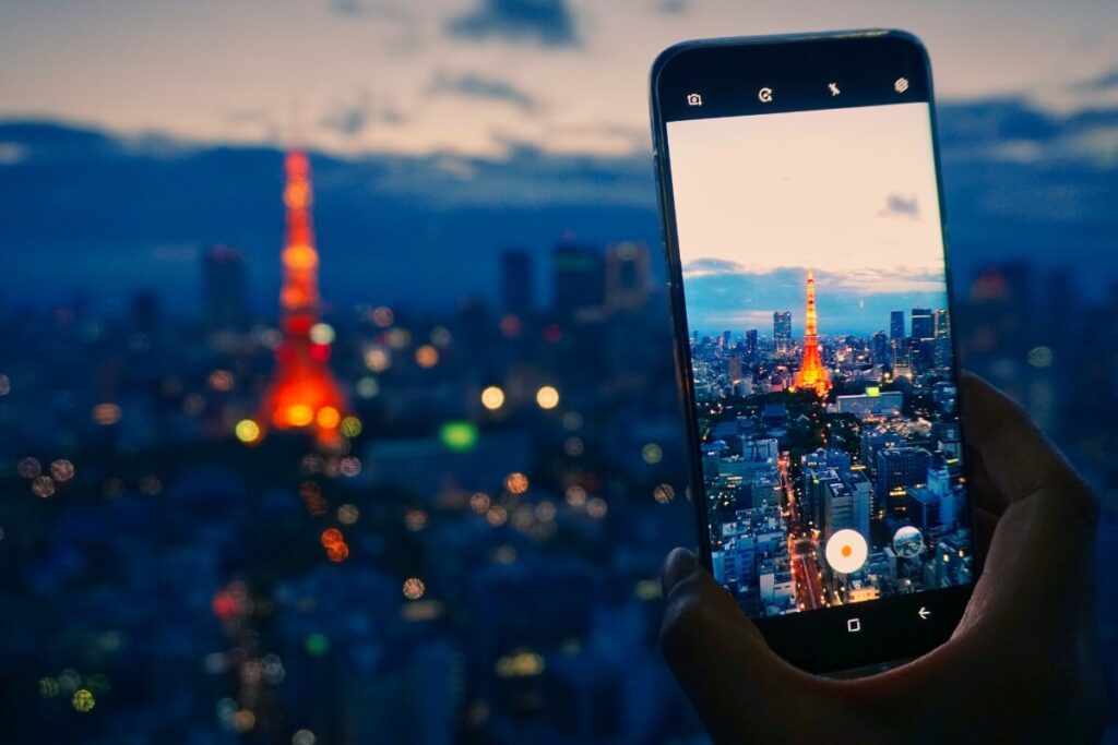 cellphone taking a photo of tokyo skyline at dusk