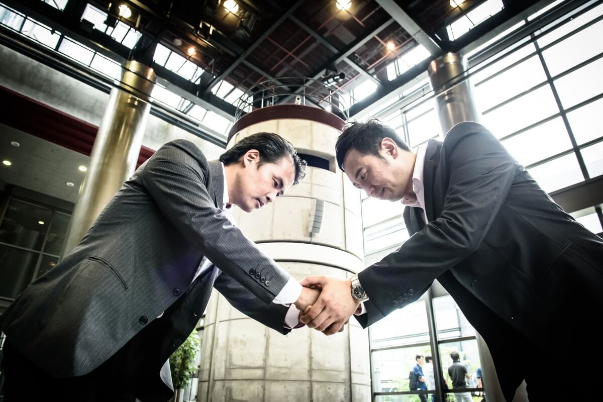 japanses businessmen bowing and shaking hands