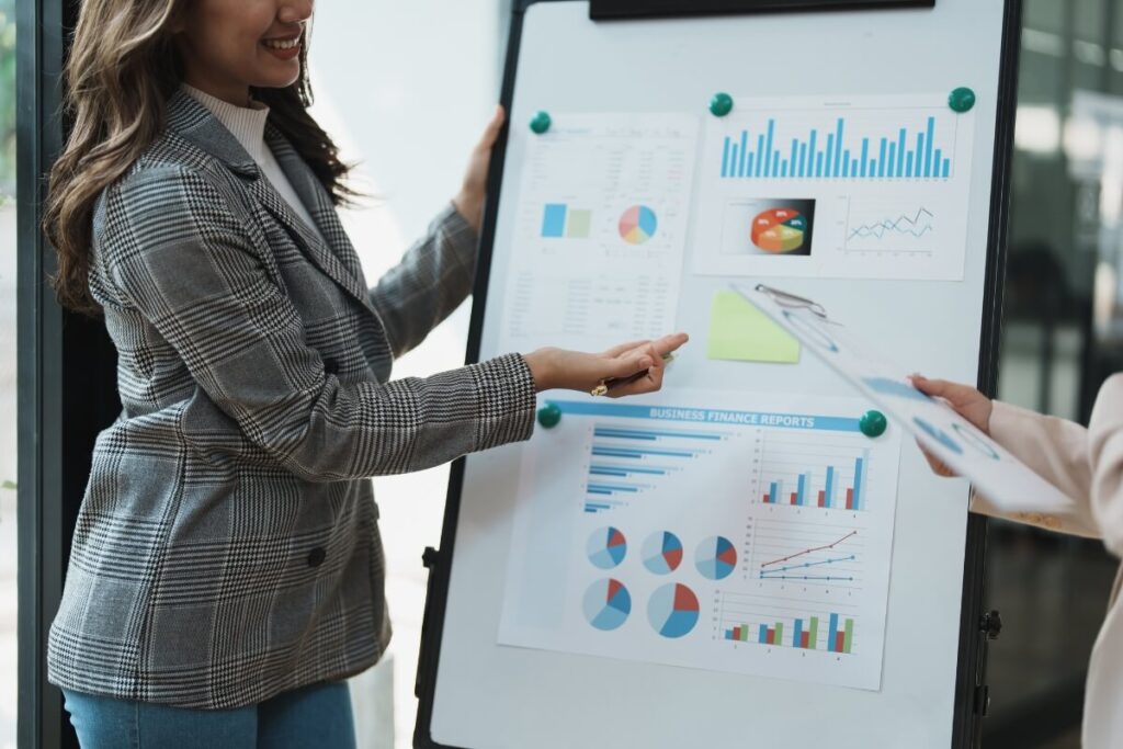 woman presenting graphs from international accounting report on white presentation board